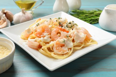 Photo of Delicious pasta with shrimps served on blue wooden table, closeup