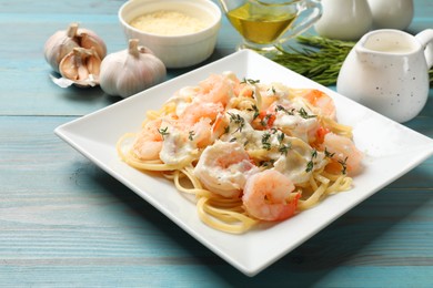 Photo of Delicious pasta with shrimps served on blue wooden table, closeup