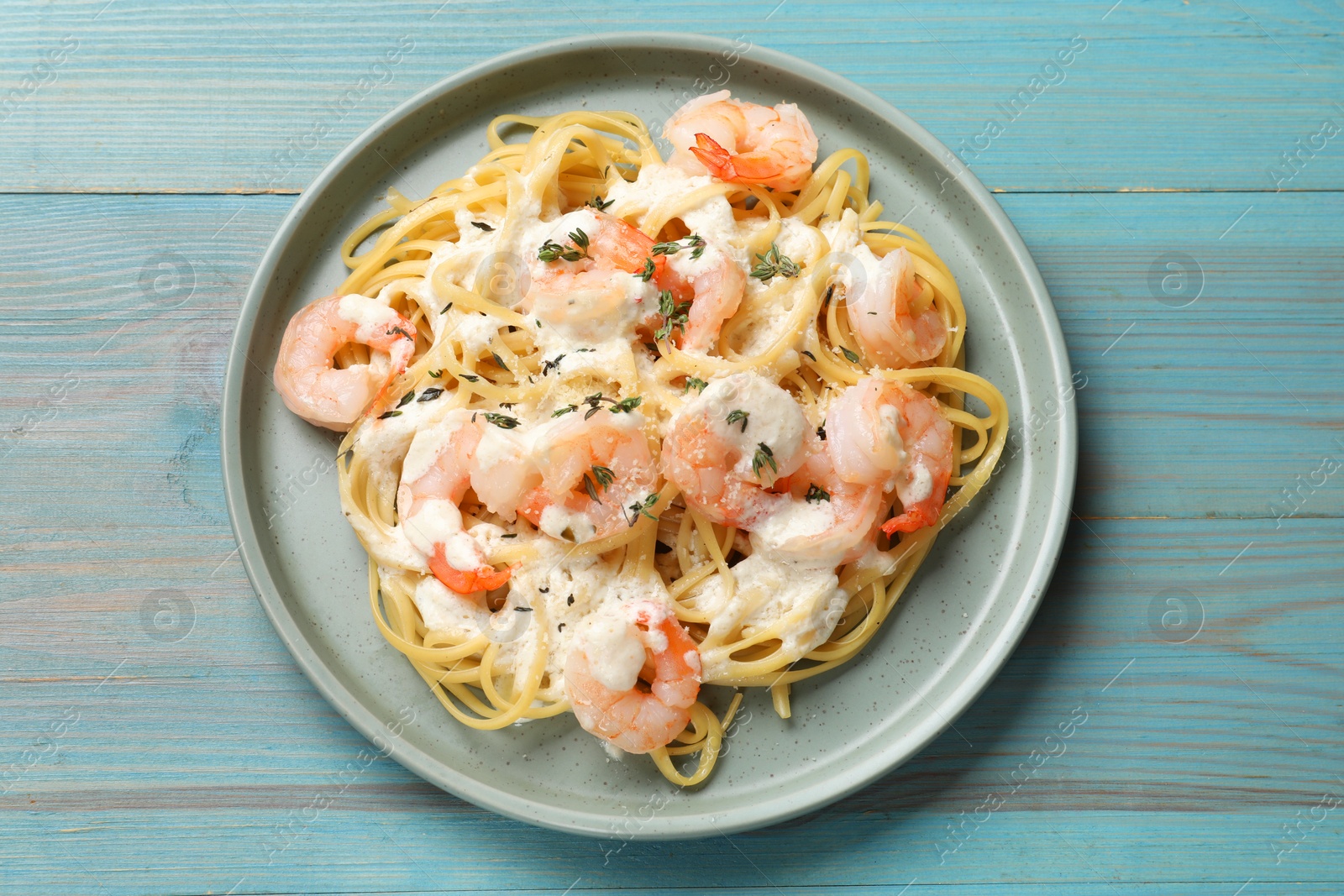 Photo of Delicious pasta with shrimps on blue wooden table, top view