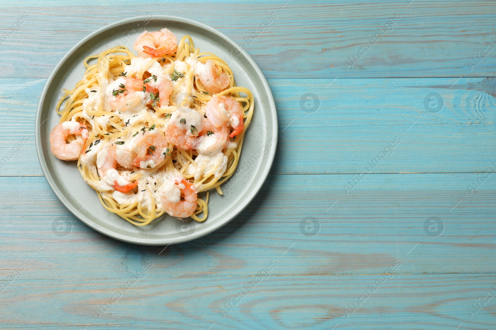 Photo of Delicious pasta with shrimps on blue wooden table, top view. Space for text