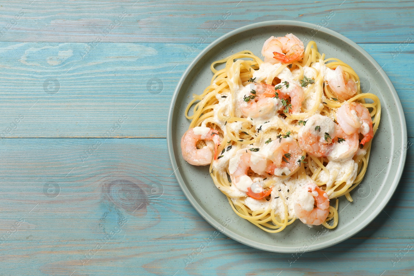 Photo of Delicious pasta with shrimps on blue wooden table, top view. Space for text