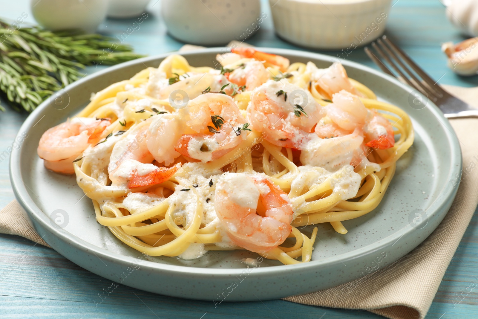 Photo of Delicious pasta with shrimps served on blue wooden table, closeup