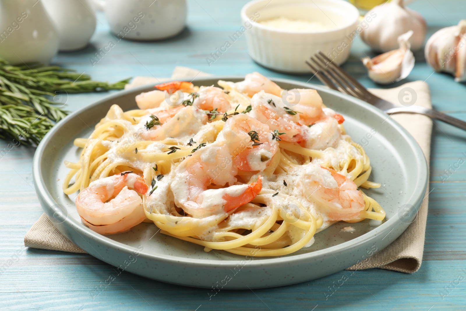 Photo of Delicious pasta with shrimps served on blue wooden table, closeup