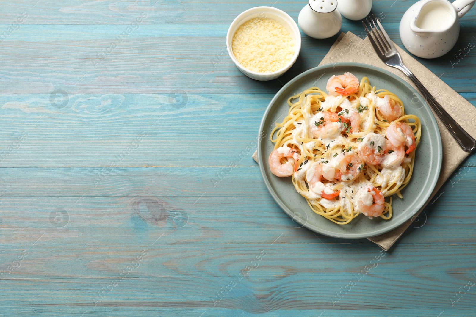 Photo of Delicious pasta with shrimps served on blue wooden table, flat lay. Space for text