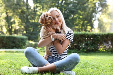 Beautiful young woman with cute dog on green grass in park