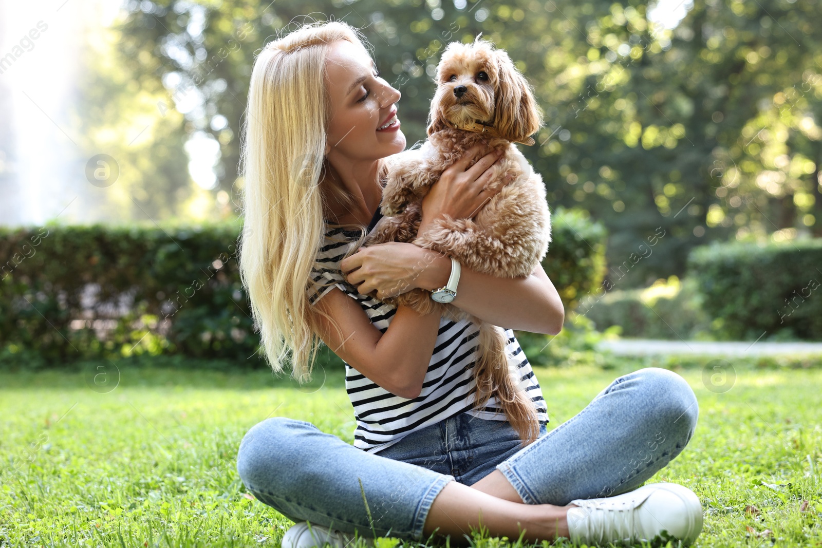 Photo of Beautiful young woman with cute dog on green grass in park