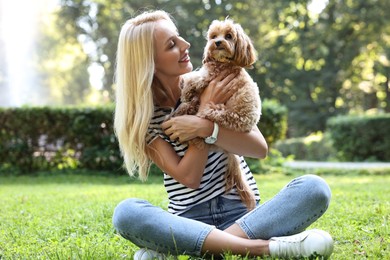 Beautiful young woman with cute dog on green grass in park