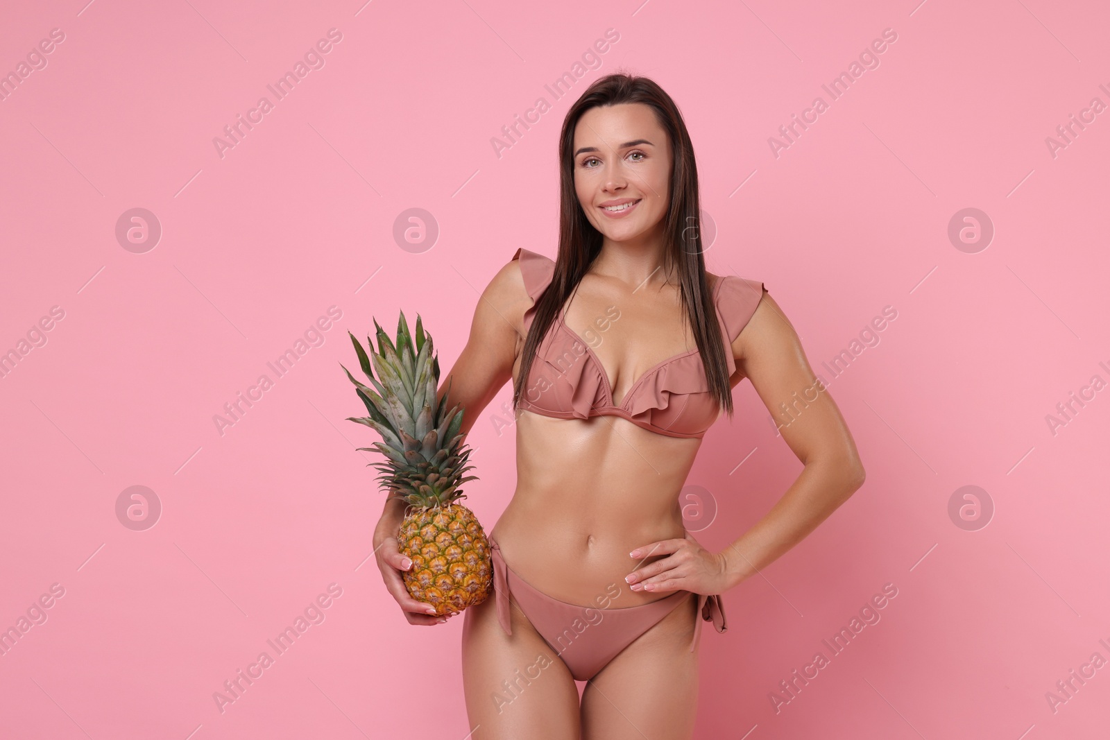 Photo of Woman in stylish bikini with fresh pineapple on pink background