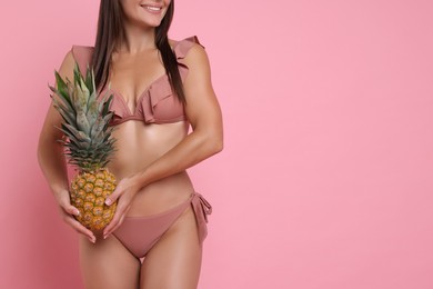 Photo of Woman in stylish bikini with fresh pineapple on pink background, closeup. Space for text