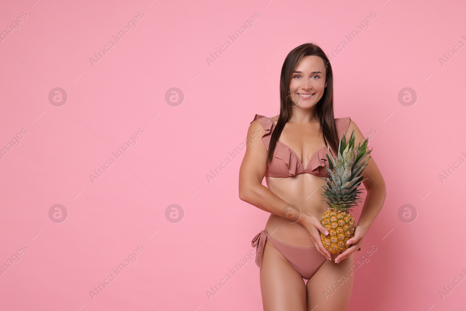 Photo of Woman in stylish bikini with fresh pineapple on pink background, space for text