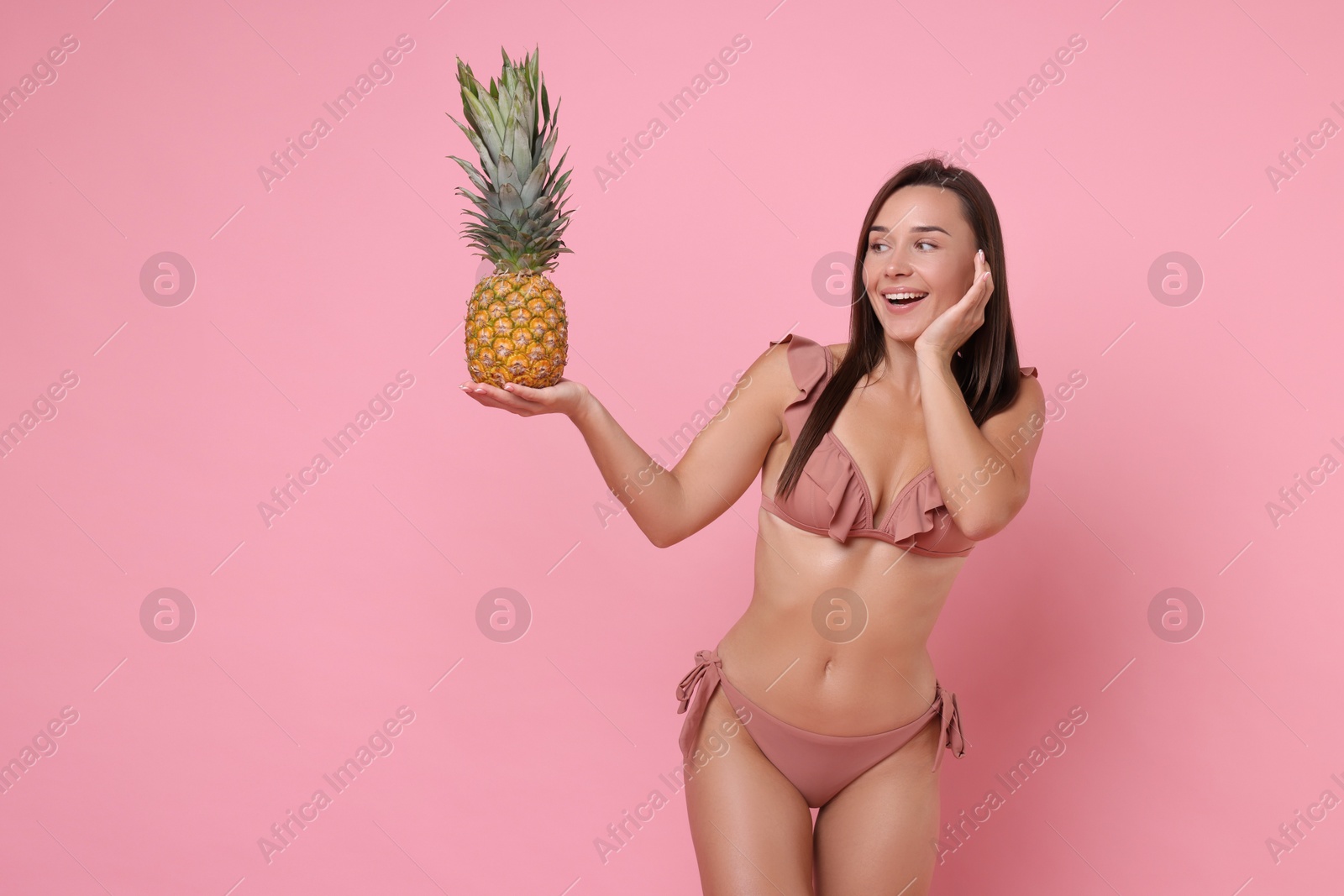 Photo of Woman in stylish bikini with fresh pineapple on pink background