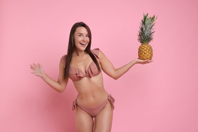 Photo of Woman in stylish bikini with fresh pineapple on pink background