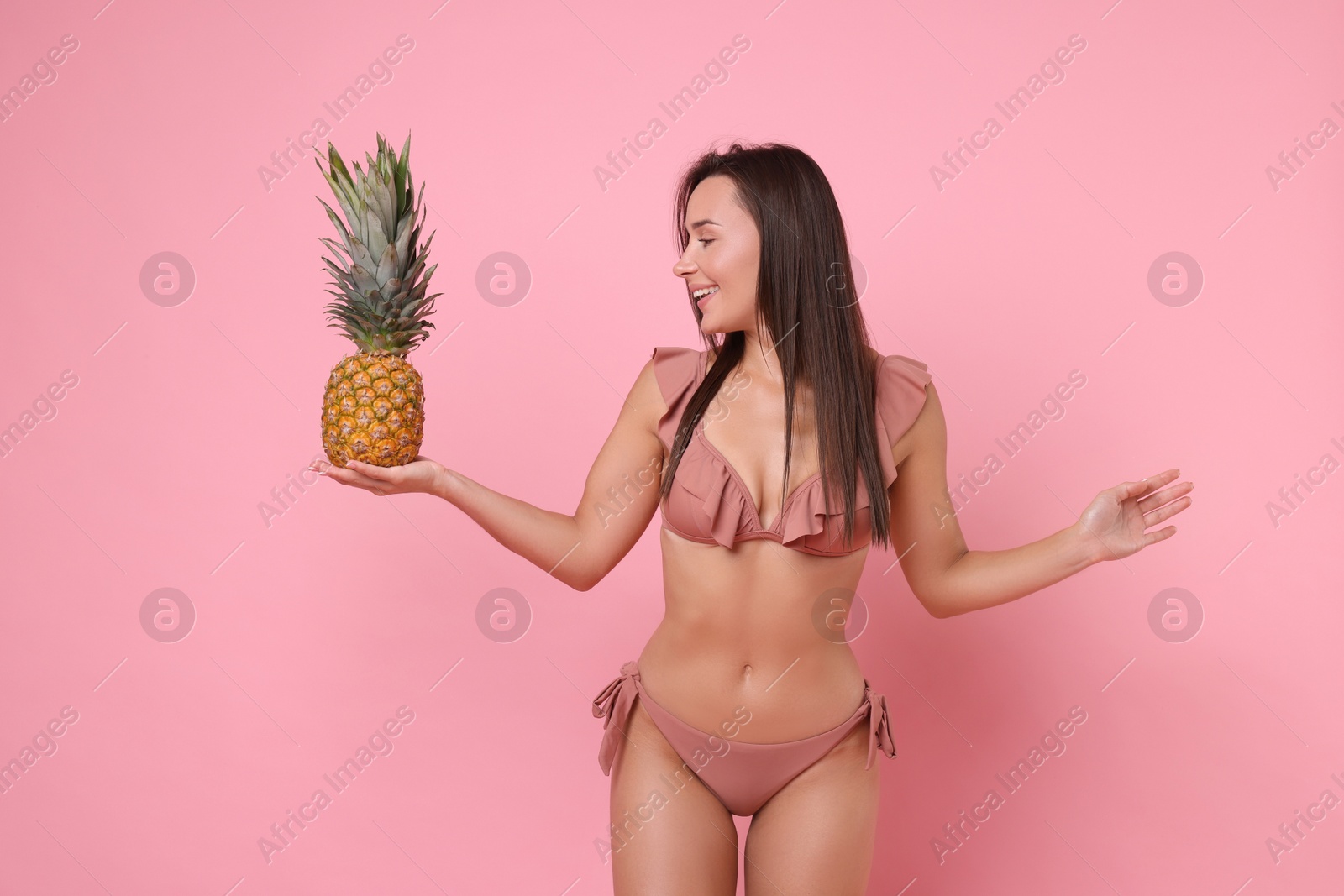 Photo of Woman in stylish bikini with fresh pineapple on pink background