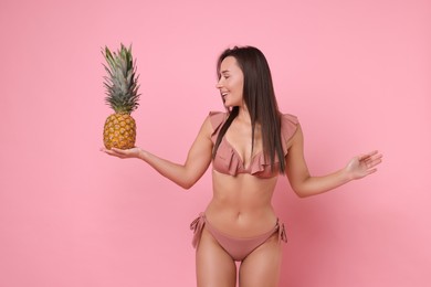 Photo of Woman in stylish bikini with fresh pineapple on pink background