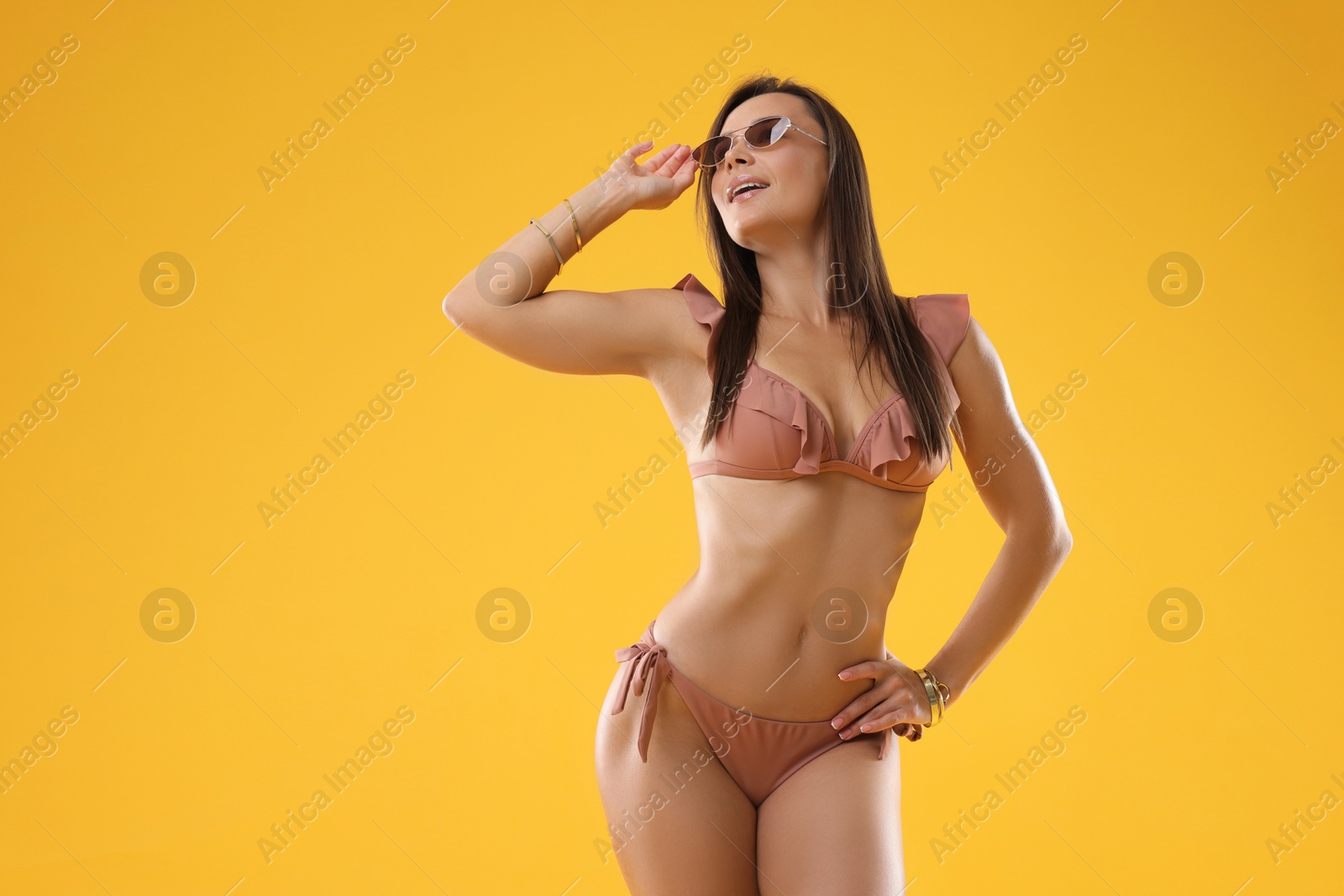 Photo of Woman in stylish bikini on orange background, space for text