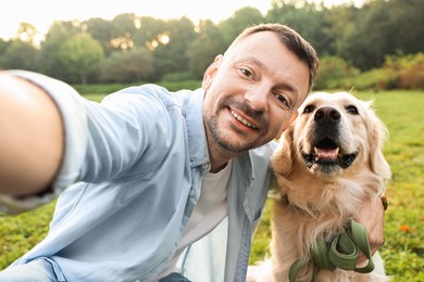 Photo of Smiling man with cute Golden Retriever dog taking selfie on spring day