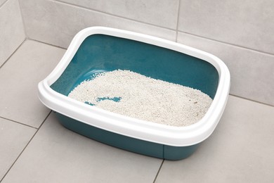 Photo of Cat litter tray with filler on floor indoors