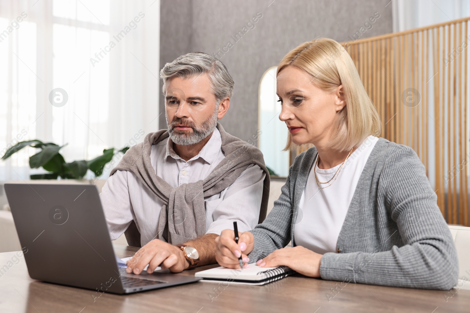 Photo of Couple planning pension budget at table indoors