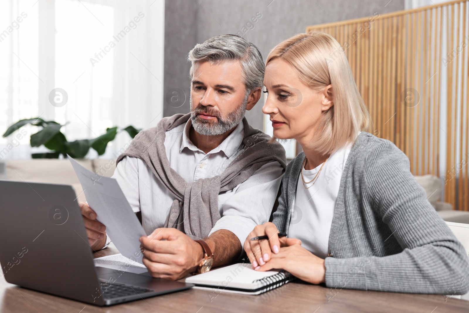 Photo of Couple planning pension budget at table indoors