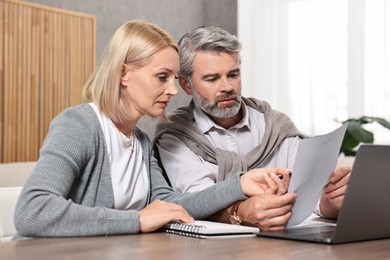 Photo of Couple planning pension budget at table indoors