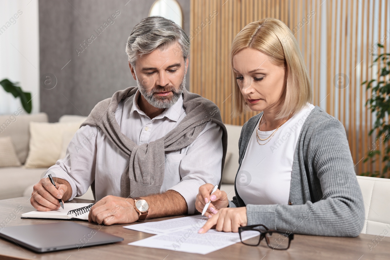 Photo of Couple planning pension budget at table indoors