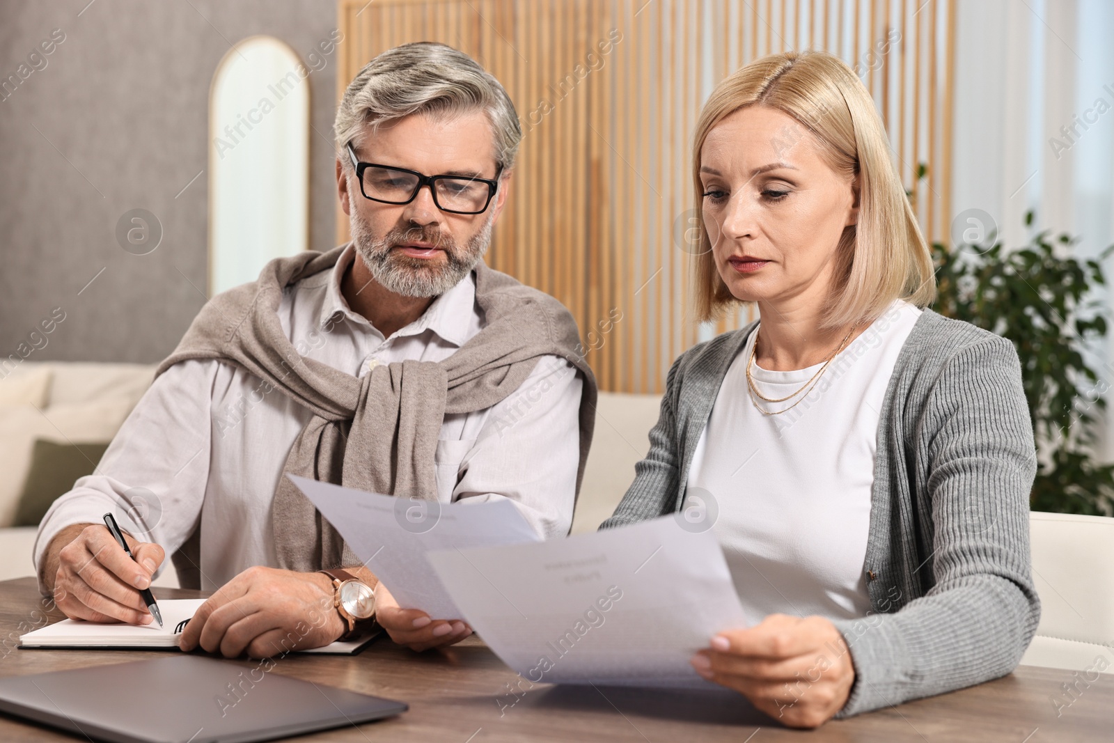 Photo of Couple planning pension budget at table indoors