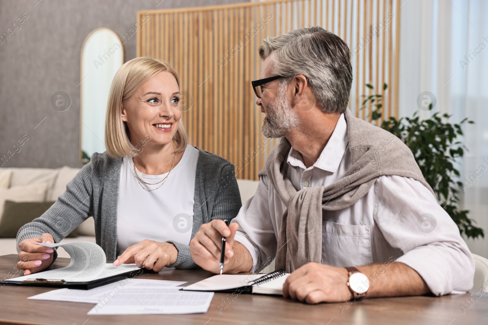 Photo of Couple planning pension budget at table indoors