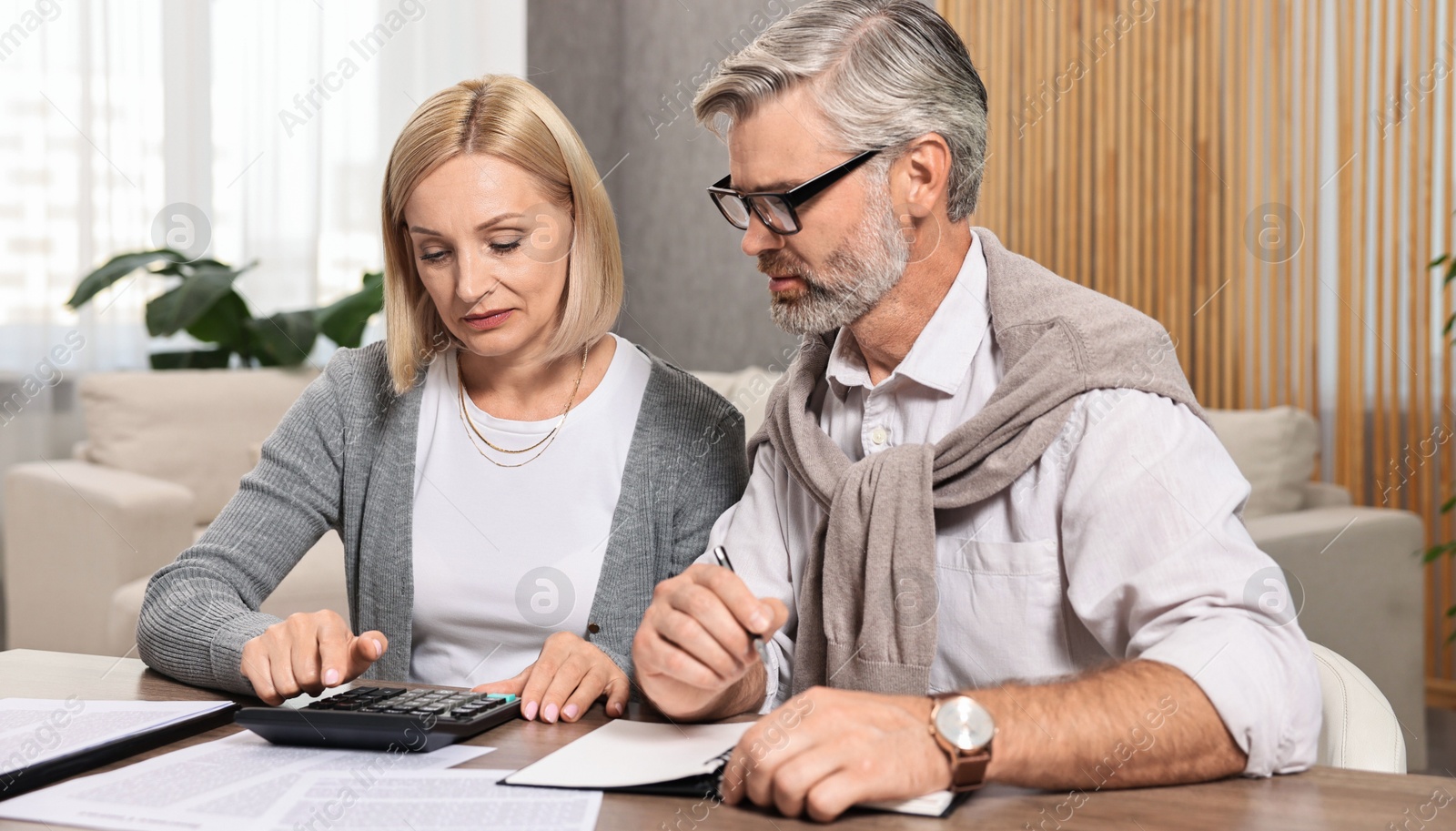 Photo of Couple planning pension budget at table indoors