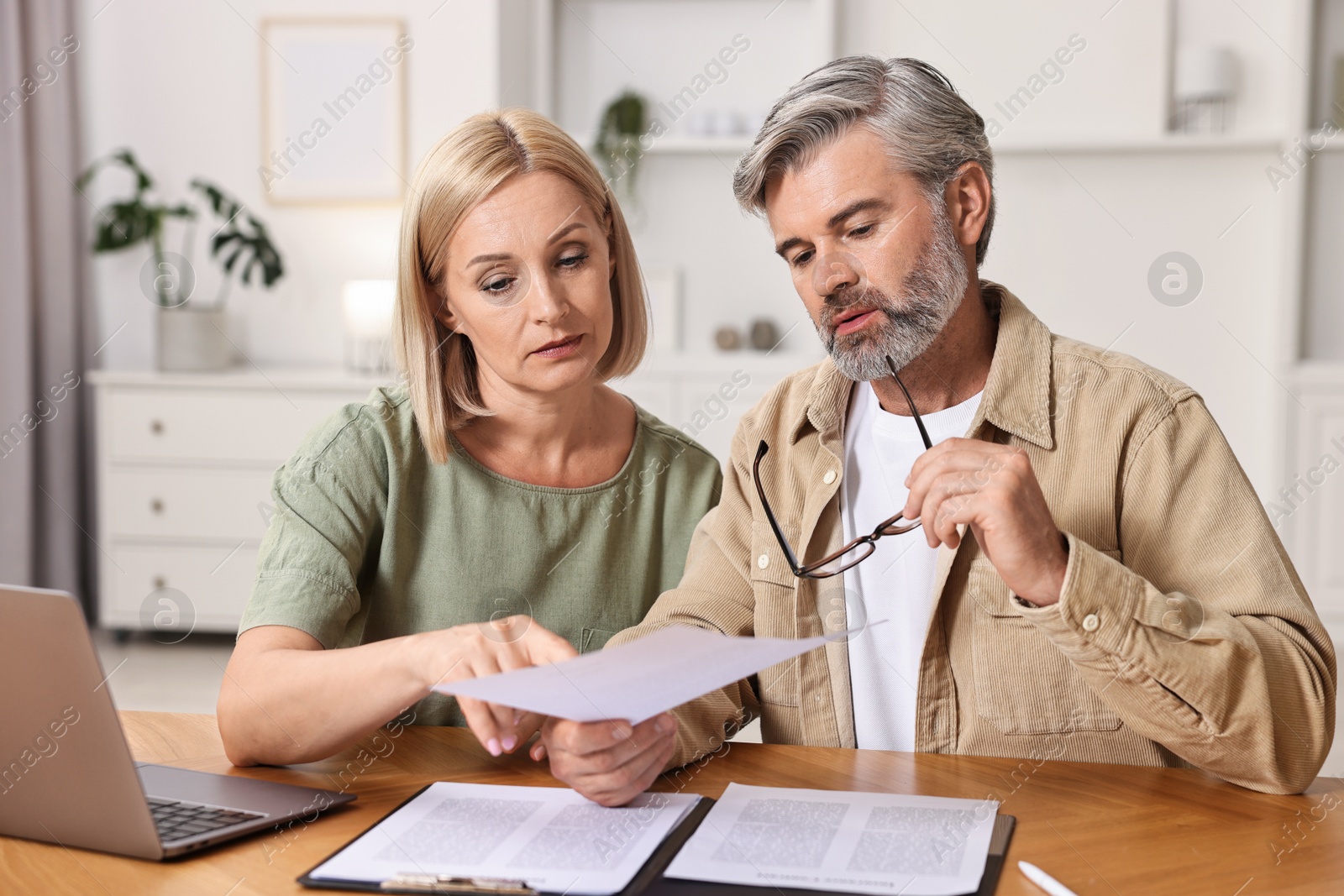 Photo of Couple planning pension budget at table indoors