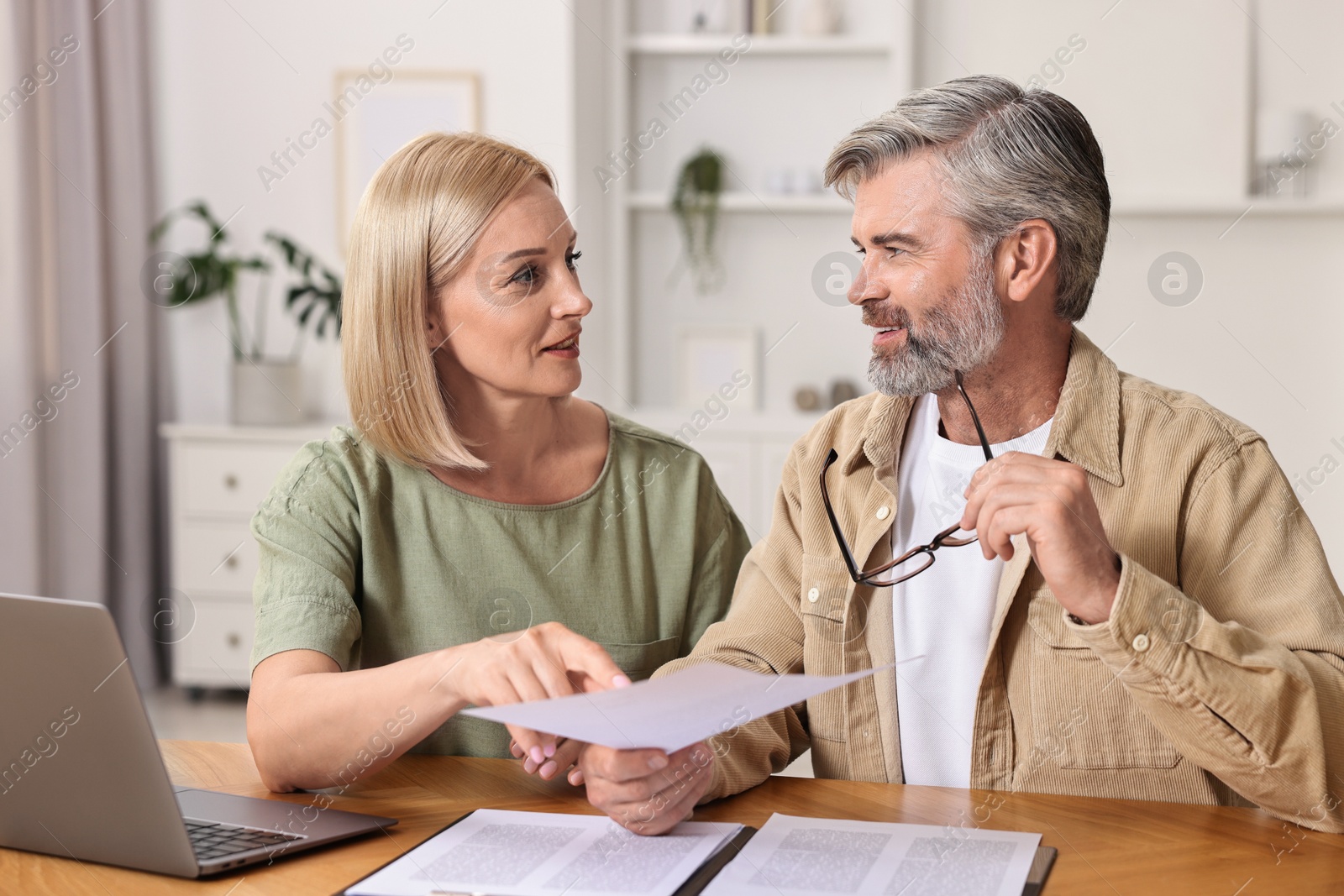 Photo of Couple planning pension budget at table indoors