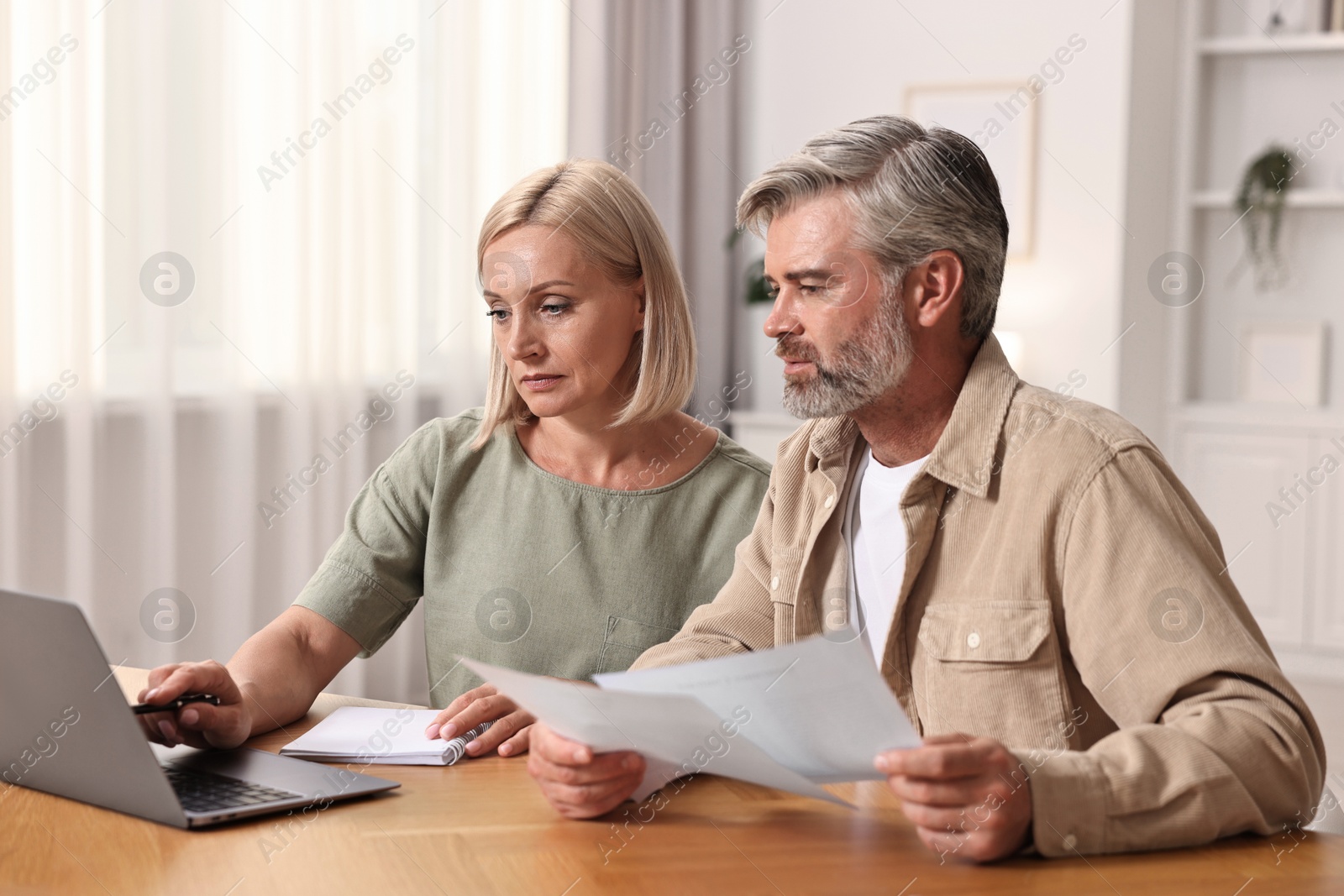 Photo of Couple planning pension budget at table indoors