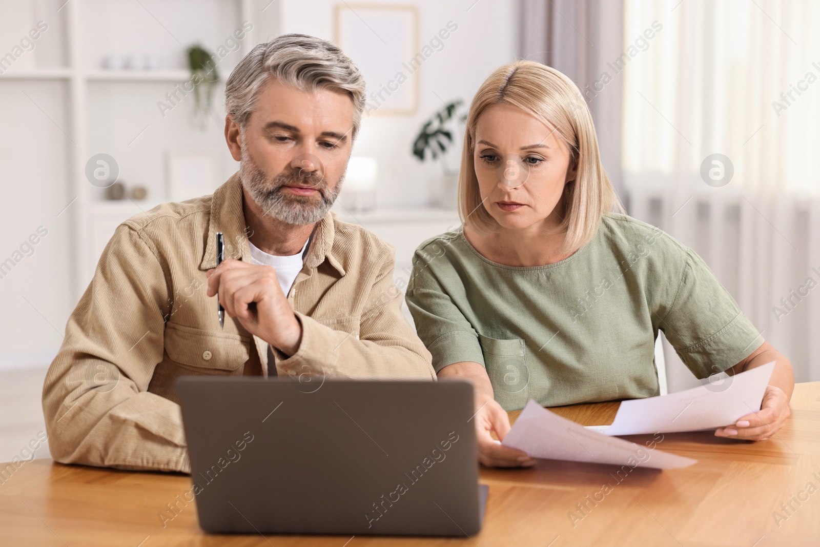 Photo of Couple planning pension budget at table indoors