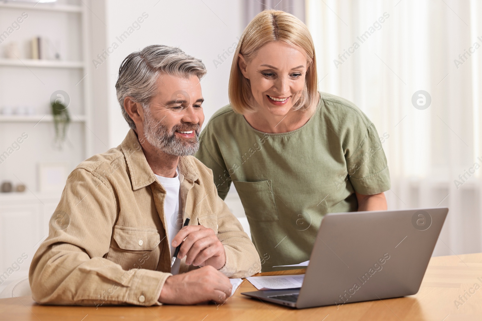 Photo of Couple planning pension budget at table indoors