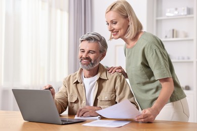 Photo of Couple planning pension budget at table indoors