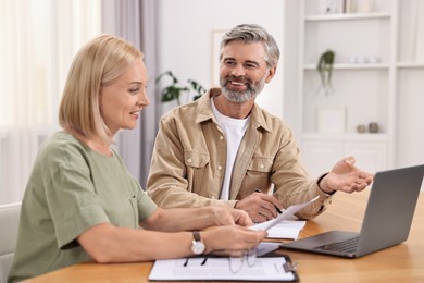 Photo of Couple planning pension budget at table indoors