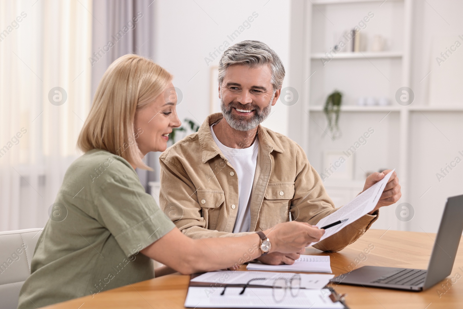 Photo of Couple planning pension budget at table indoors