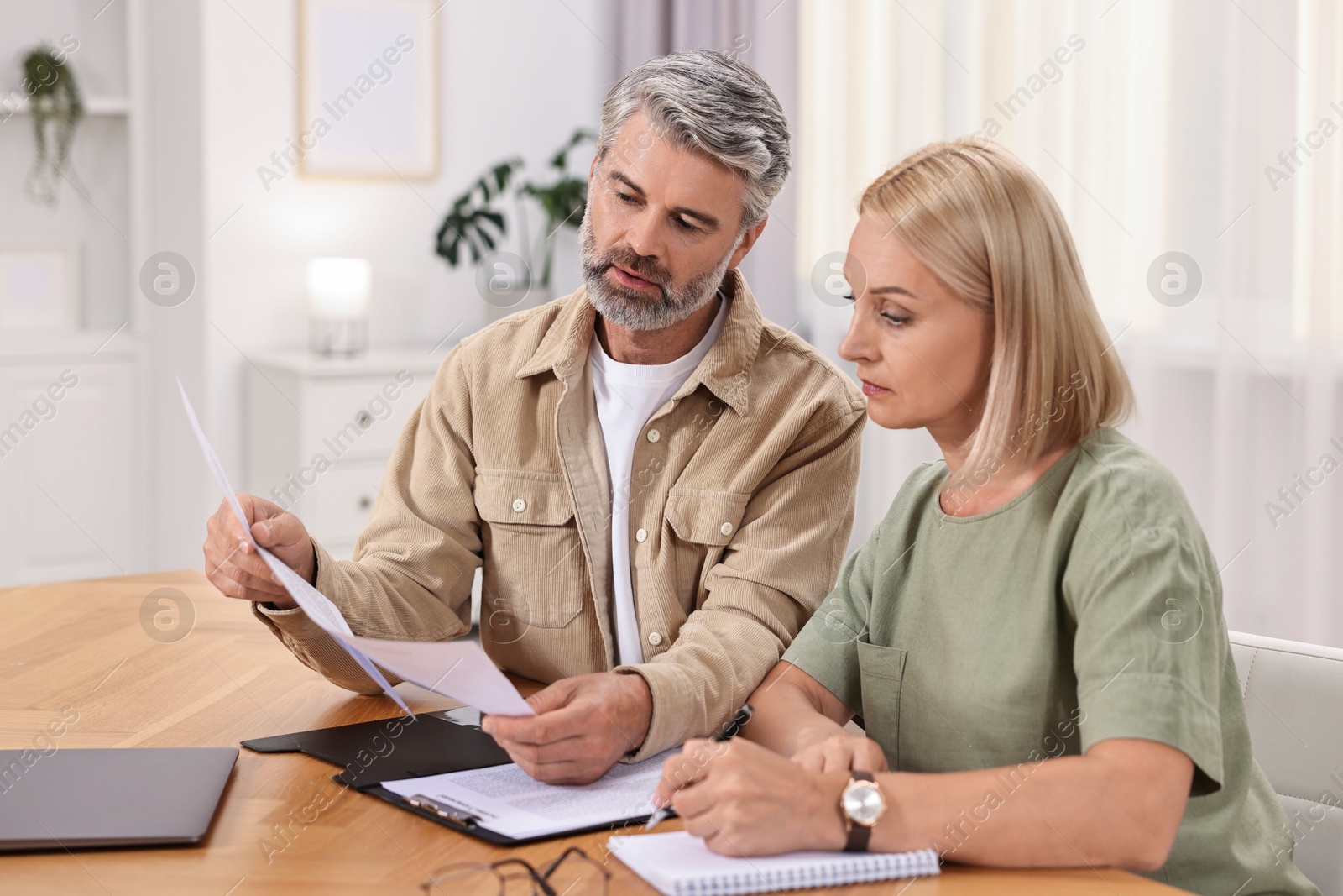 Photo of Couple planning pension budget at table indoors