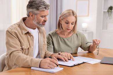 Photo of Couple planning pension budget at table indoors