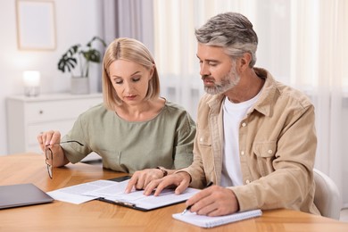 Photo of Couple planning pension budget at table indoors