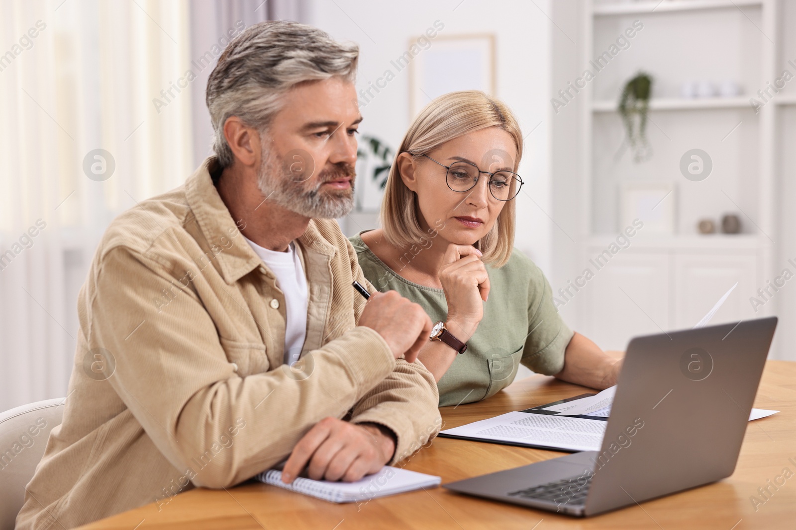 Photo of Couple planning pension budget at table indoors