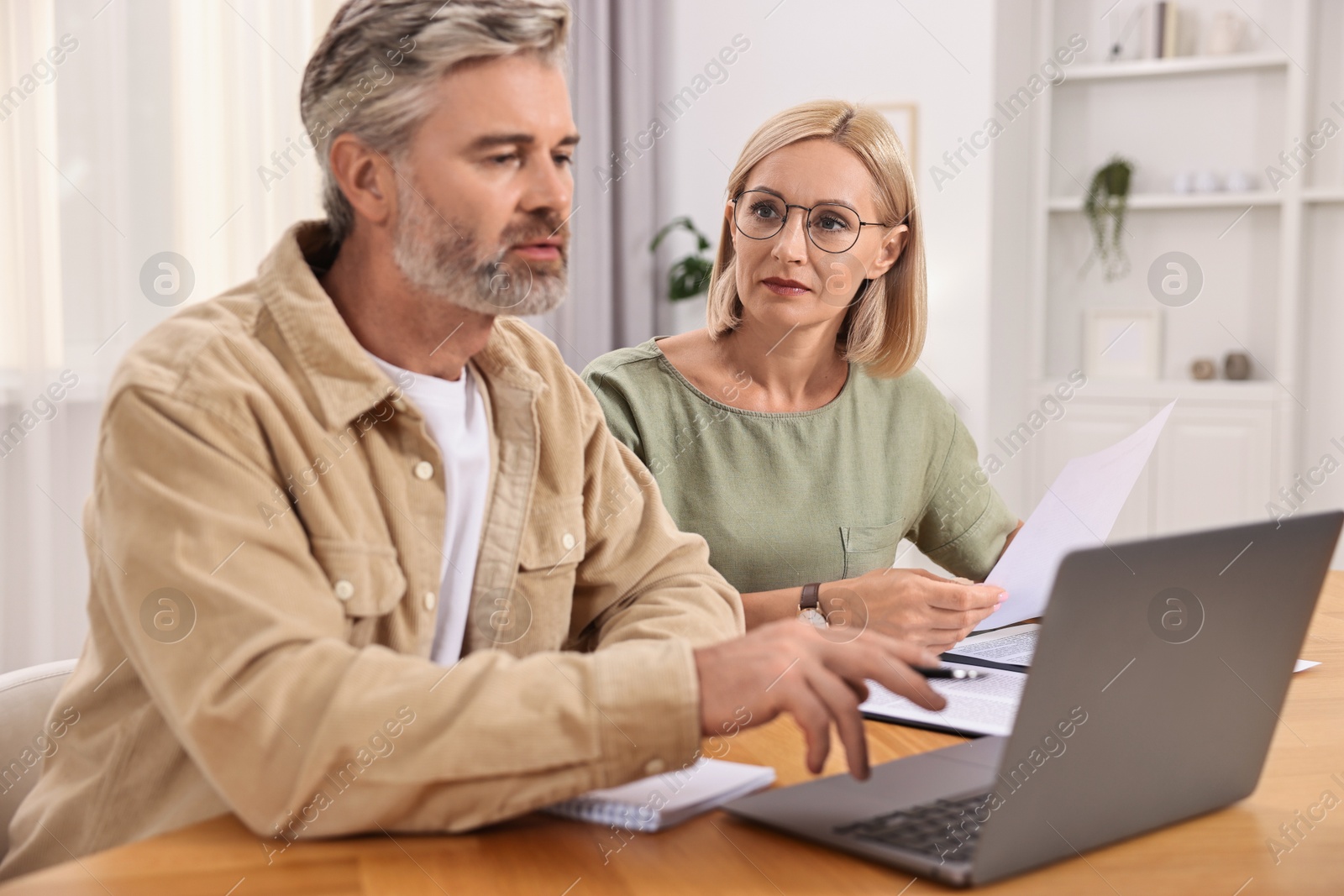 Photo of Pension savings. Couple planning budget at table indoors