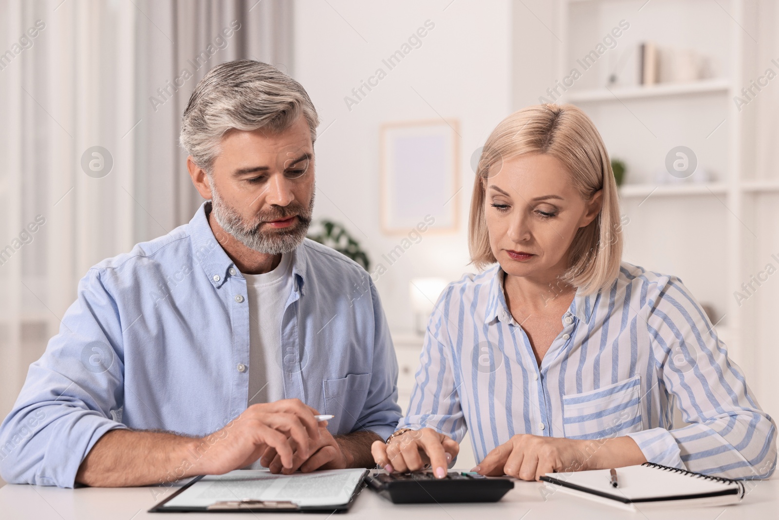 Photo of Pension savings. Couple planning budget at table indoors