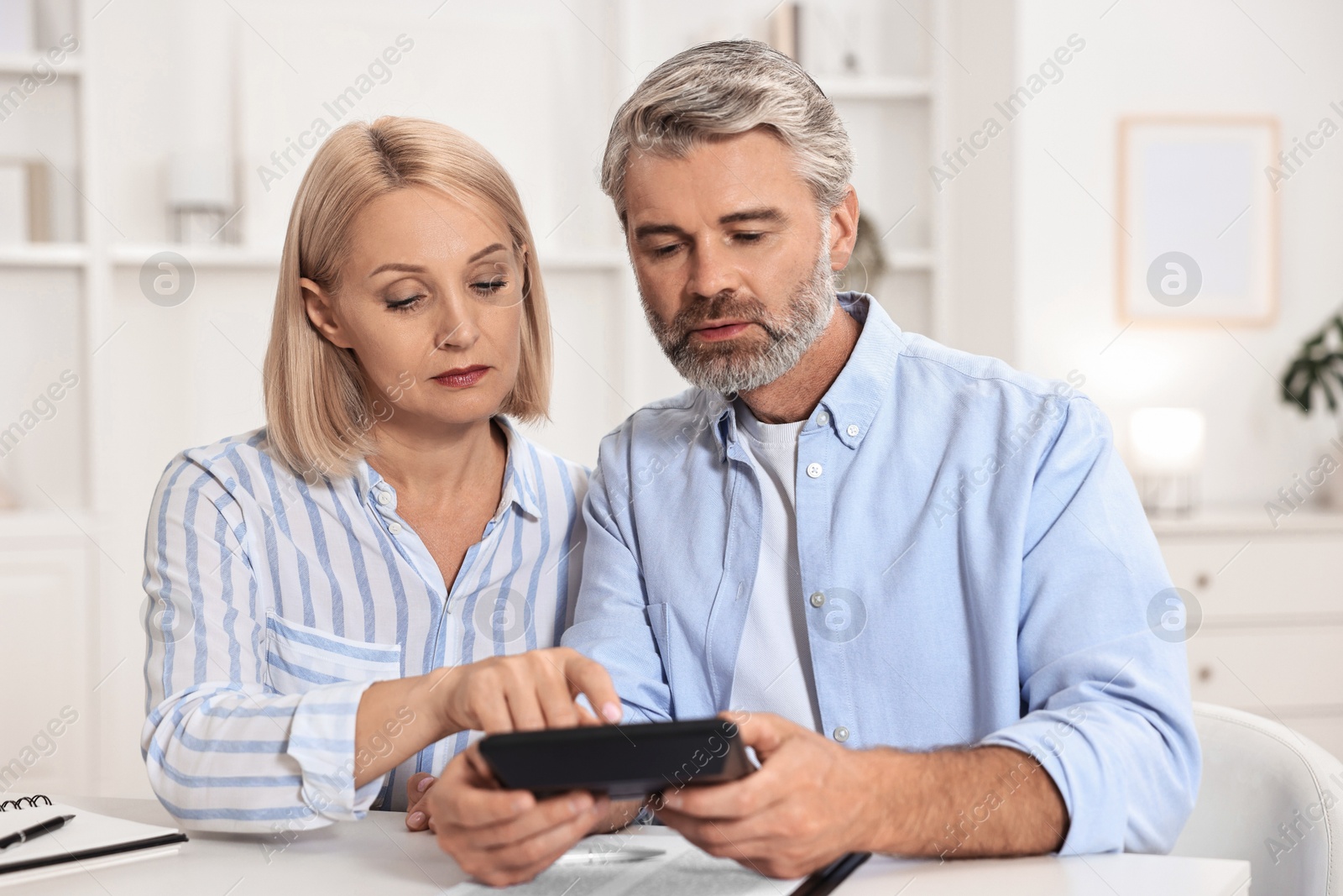 Photo of Pension savings. Couple planning budget at table indoors