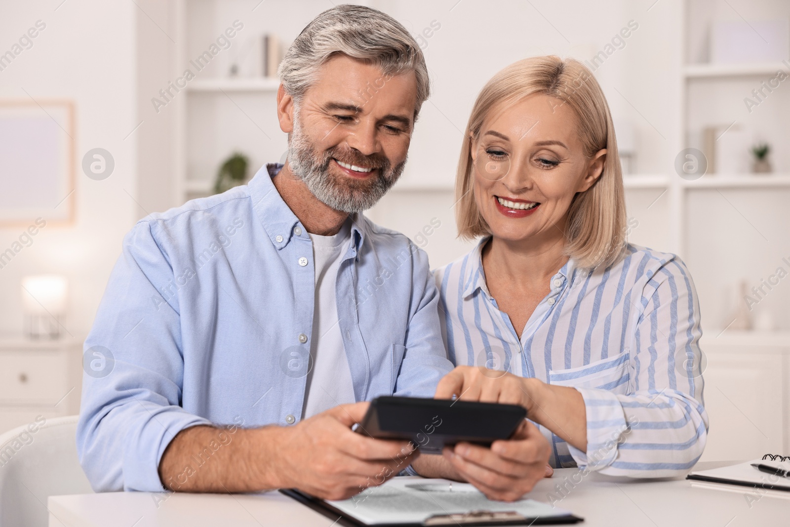 Photo of Pension savings. Couple planning budget at table indoors