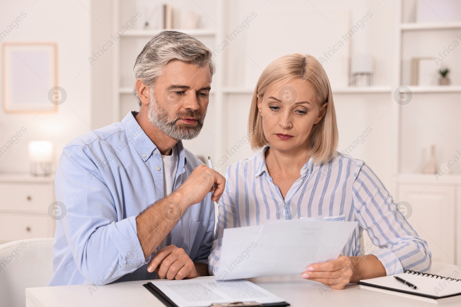 Photo of Pension savings. Couple planning budget at table indoors