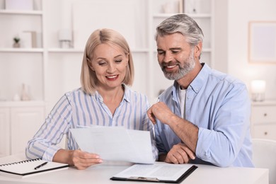 Photo of Pension savings. Couple planning budget at table indoors