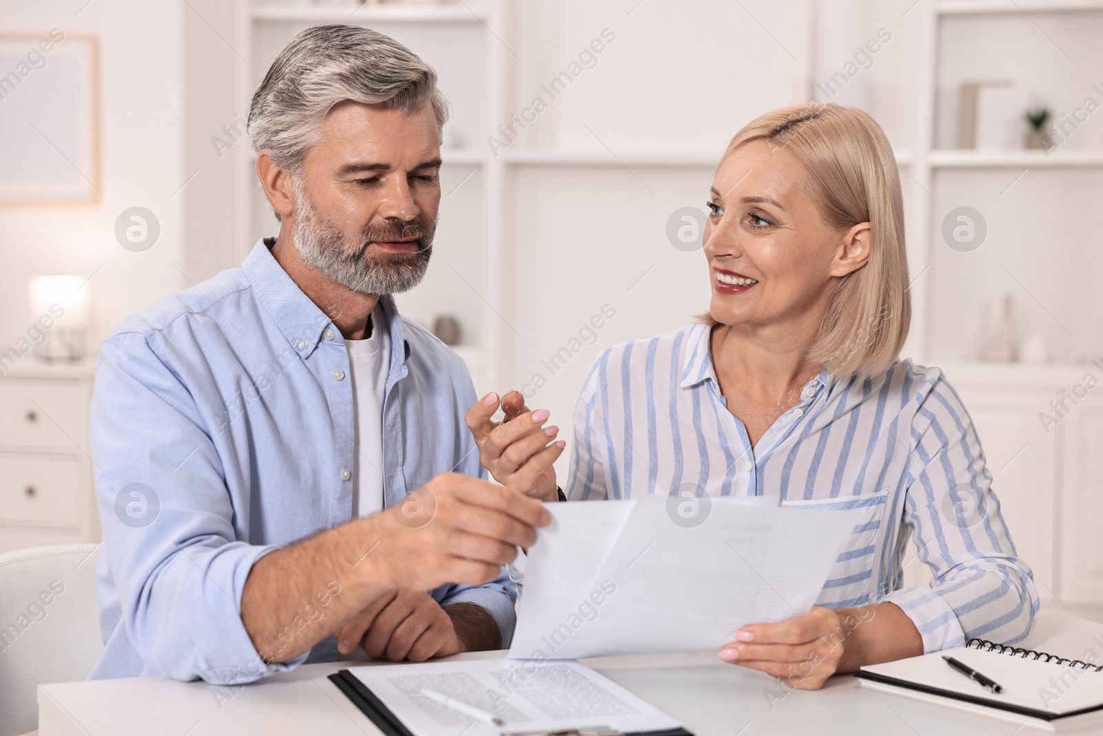 Photo of Pension savings. Couple planning budget at table indoors