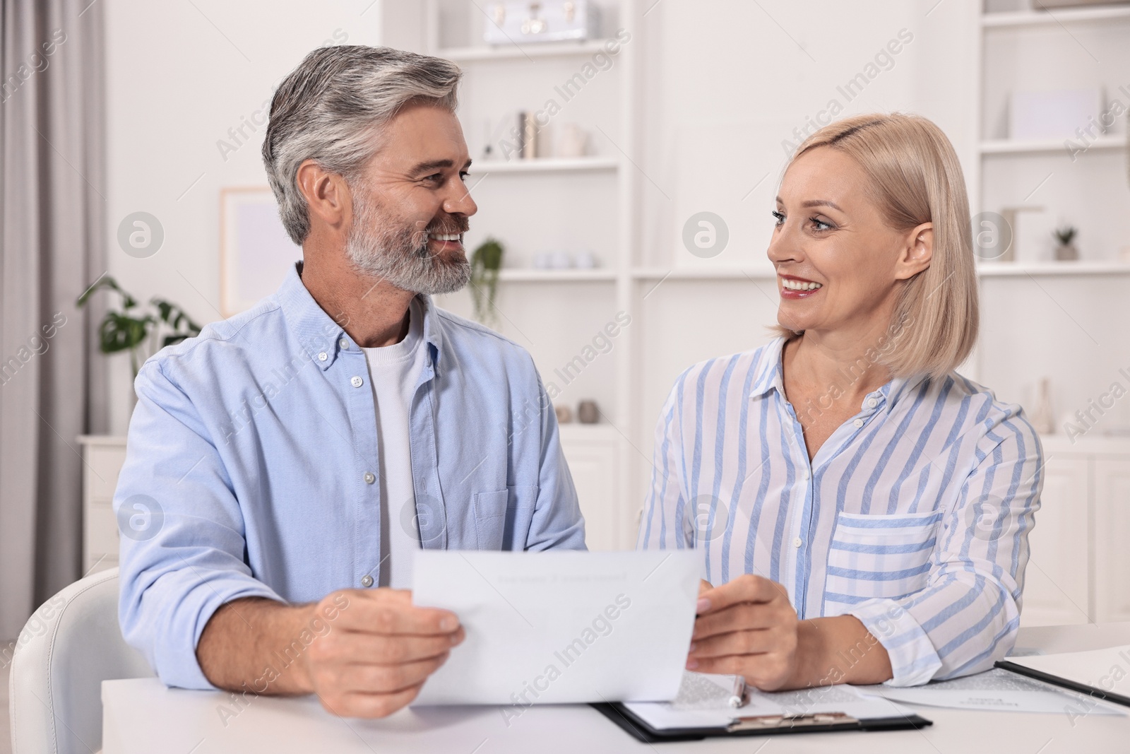 Photo of Pension savings. Couple planning budget at table indoors