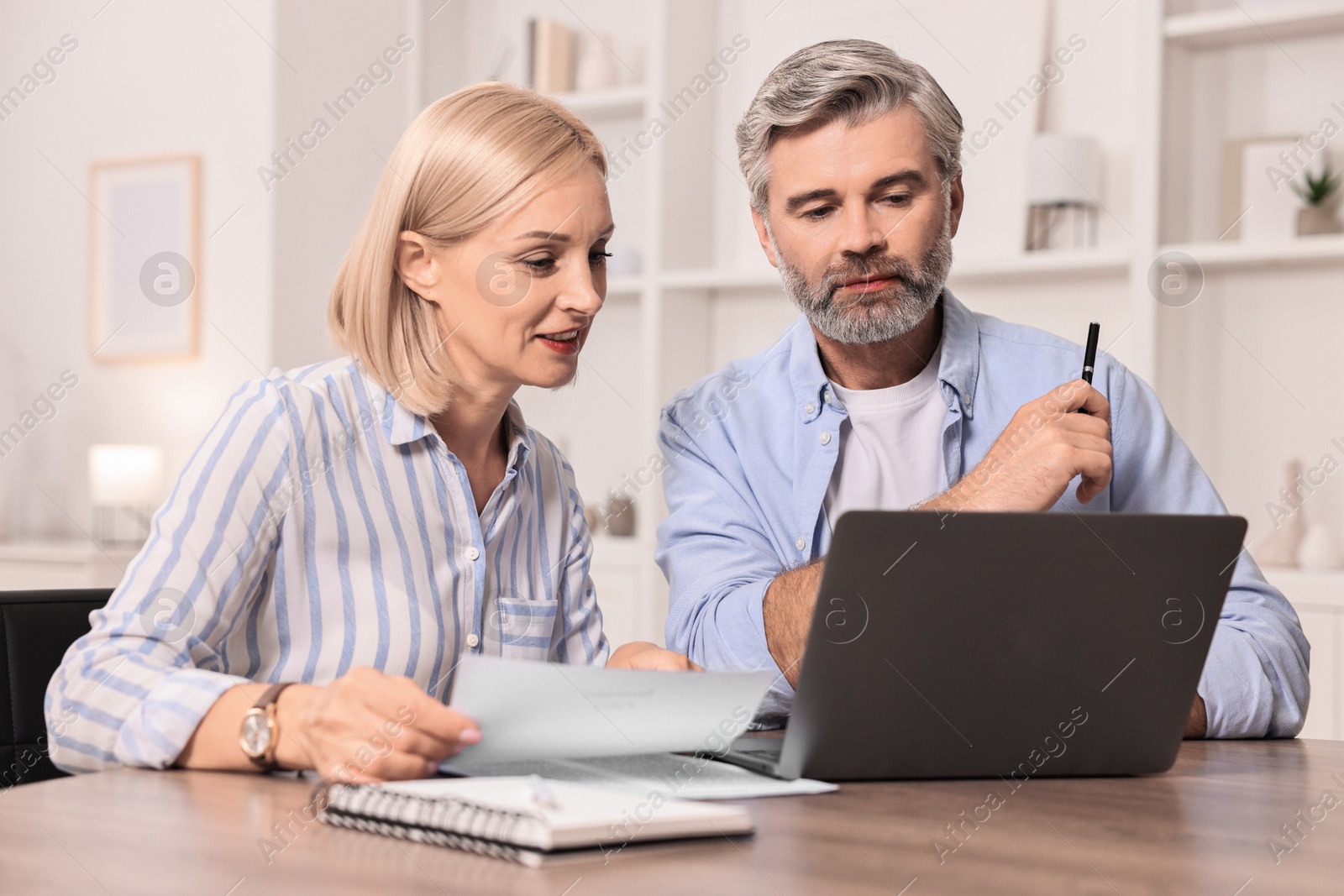 Photo of Pension savings. Couple planning budget at table indoors