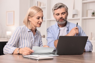 Photo of Pension savings. Couple planning budget at table indoors